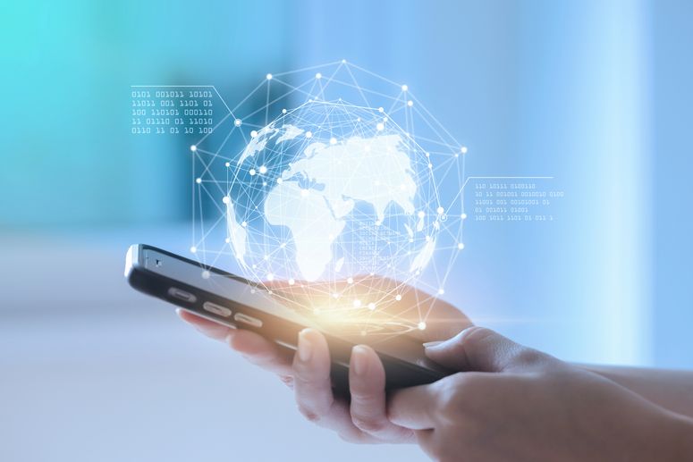 Persona sostiene smartphone con holograma del mundo