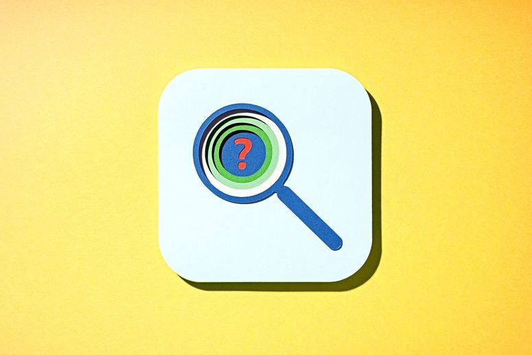 Multi layered paper cut outs of a blue and green magnifying glass with a red question mark in the center on a yellow background